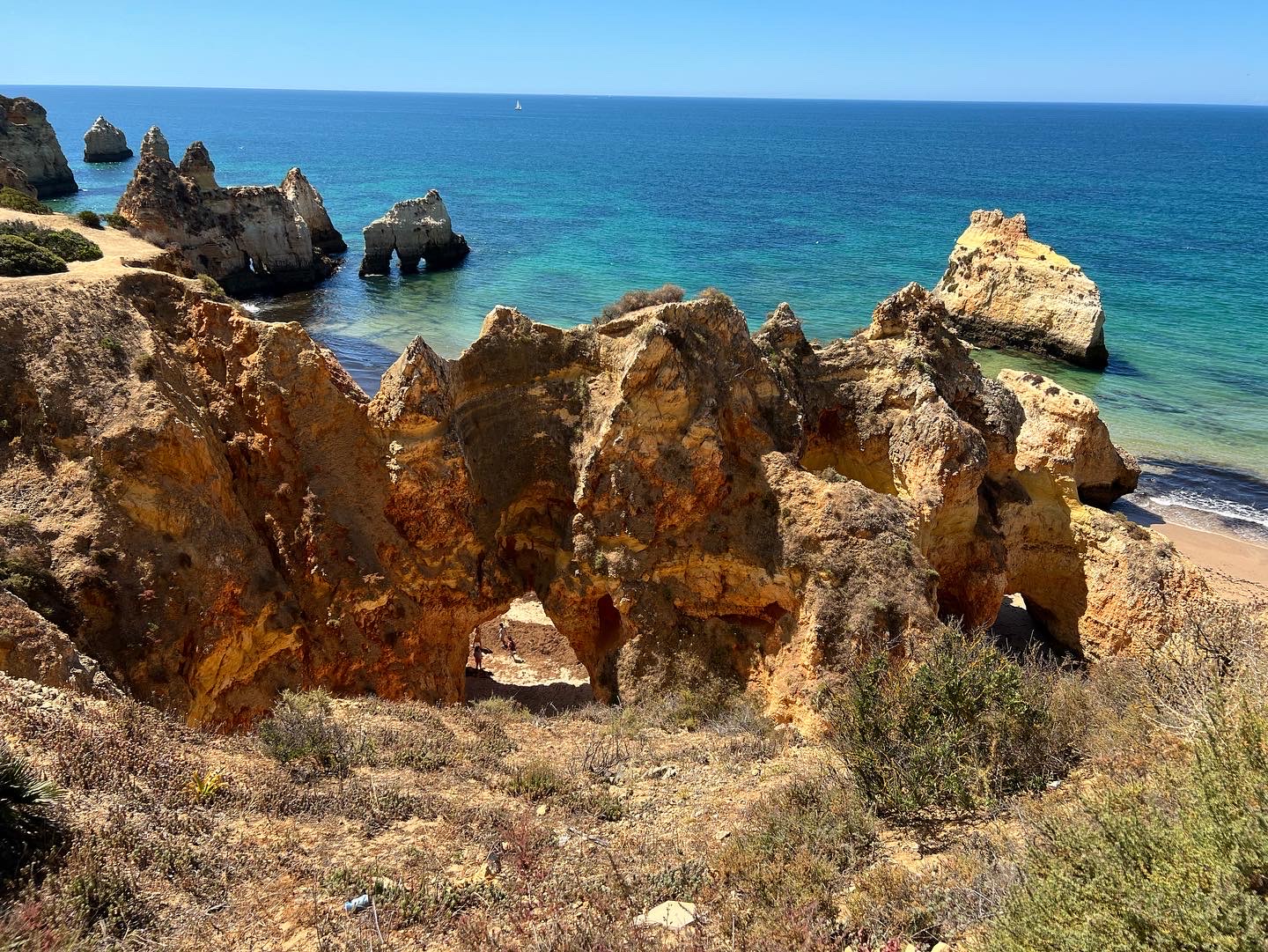 Golden rock formations against a brilliant blue ocean in The Algarve, Portugal, on a bright sunny day